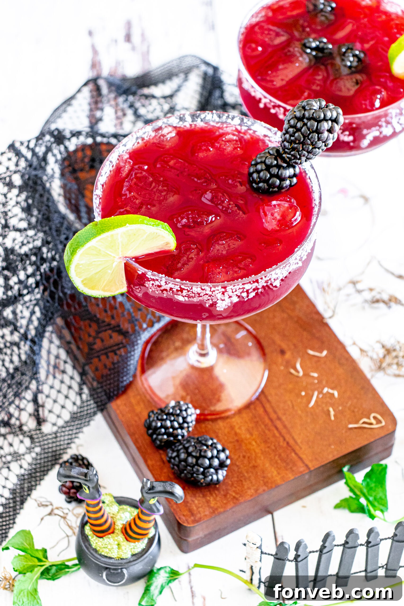 Magic Potion Margarita 5 A single Sanderson Sisters Margarita glass on a cutting board, ready to be enjoyed, with ingredients blurred in the background.