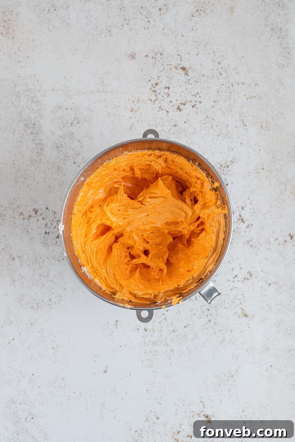 Orange marshmallow fluff in a container, perfectly whipped and ready for piping.