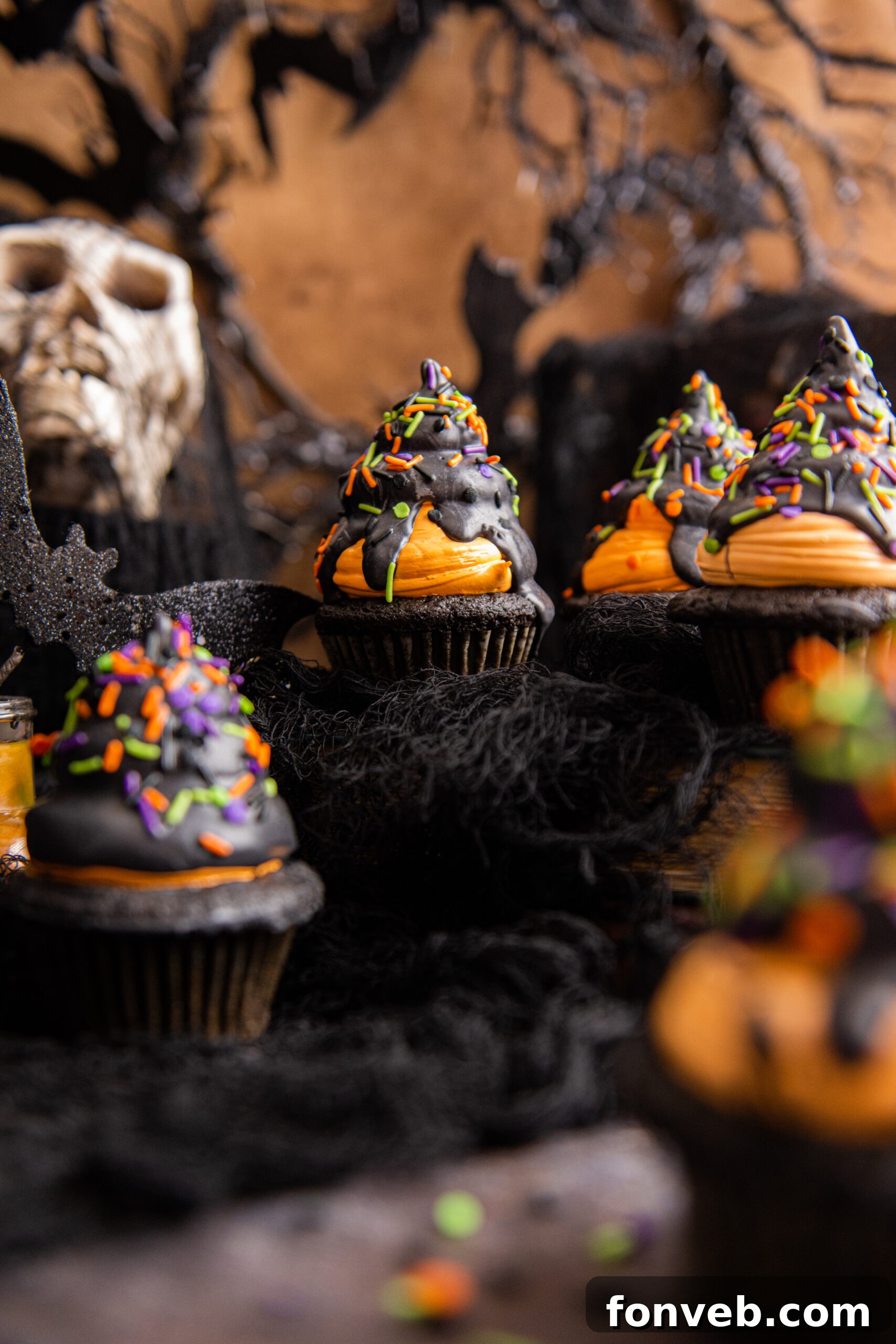 Halloween Cupcakes on a black table with Halloween decor around it, creating a festive atmosphere.