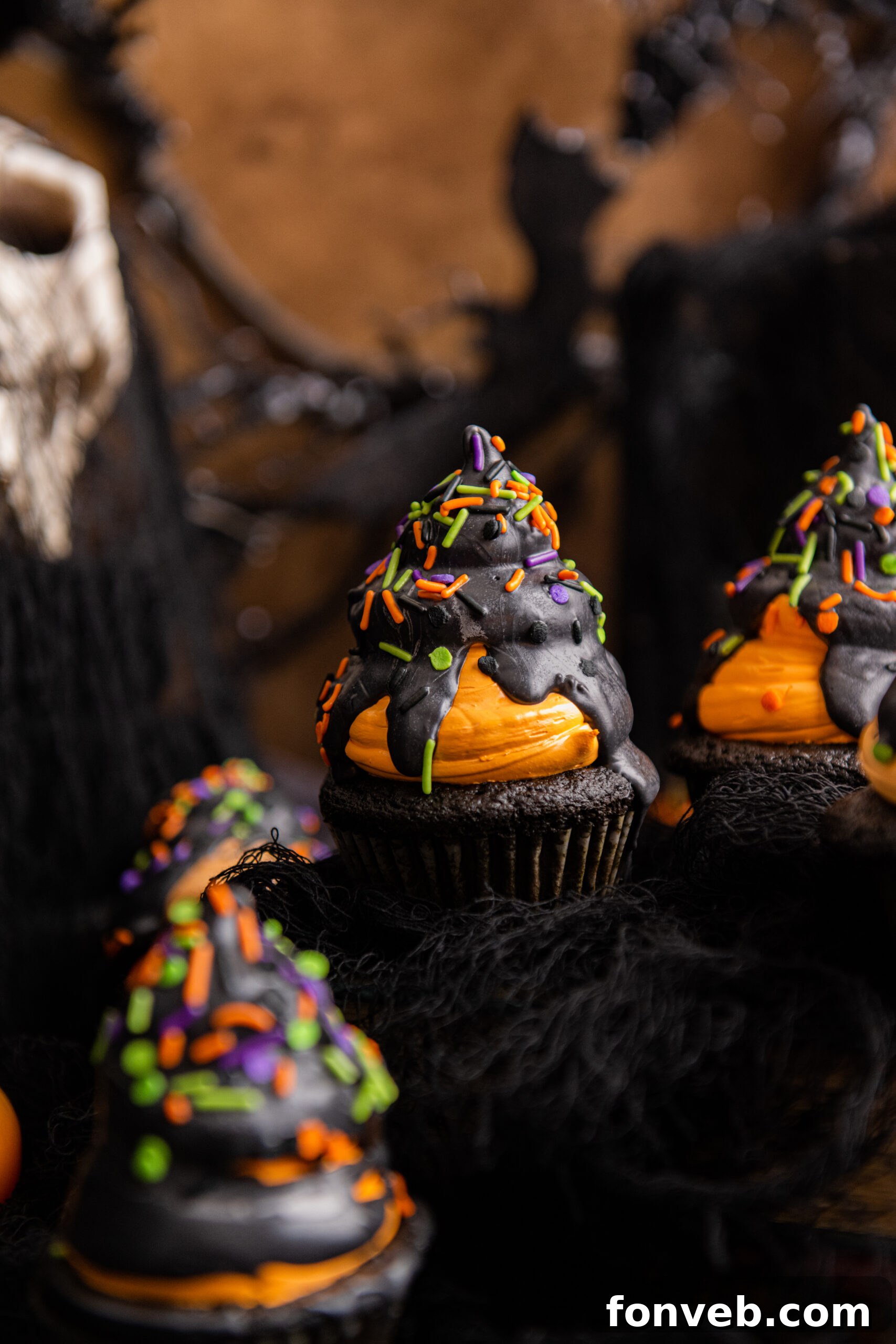 Halloween Cupcakes topped with black chocolate hard shell and festive sprinkles, ready to be enjoyed.