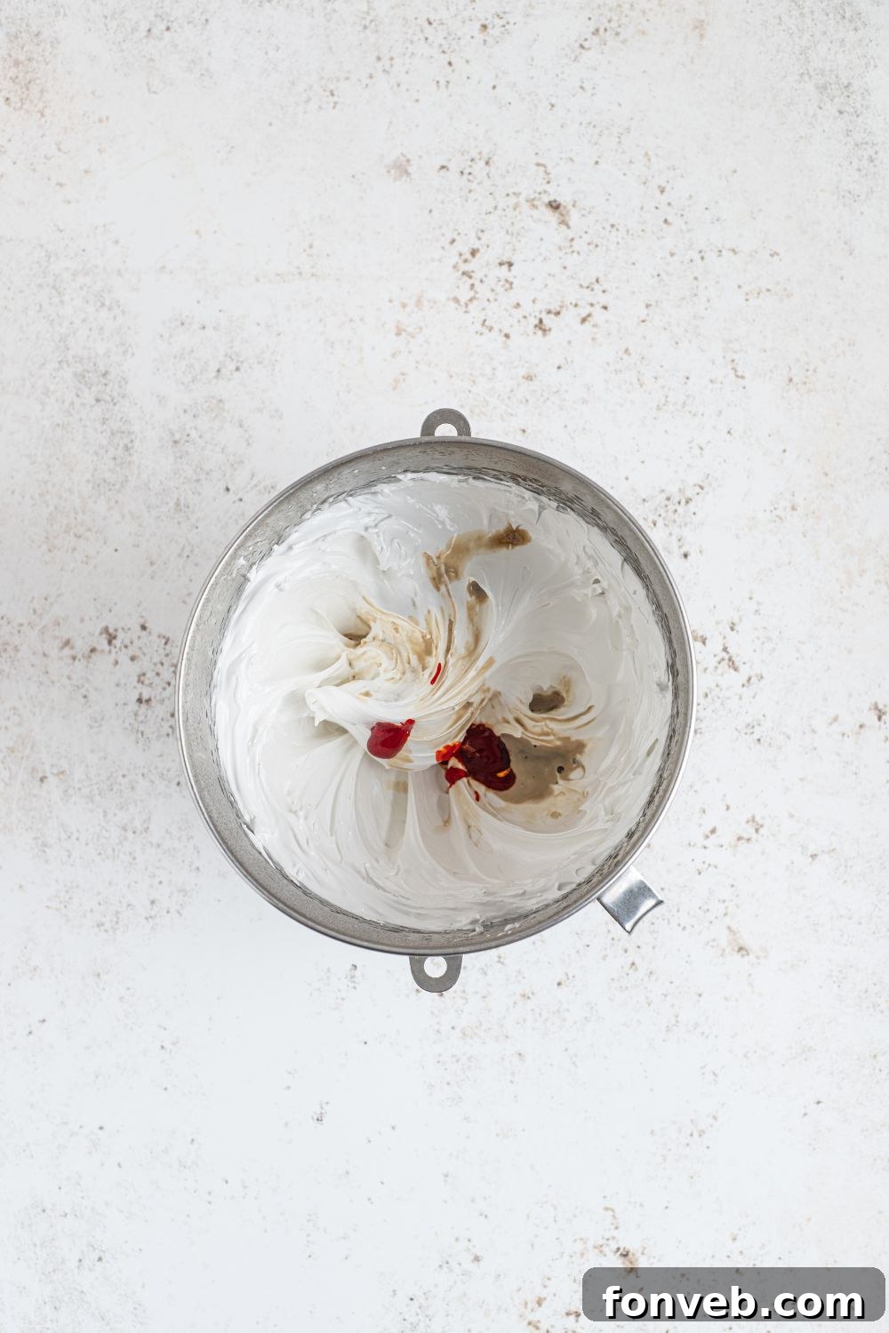 Process of making marshmallow fluff, adding vanilla extract to the mixture.