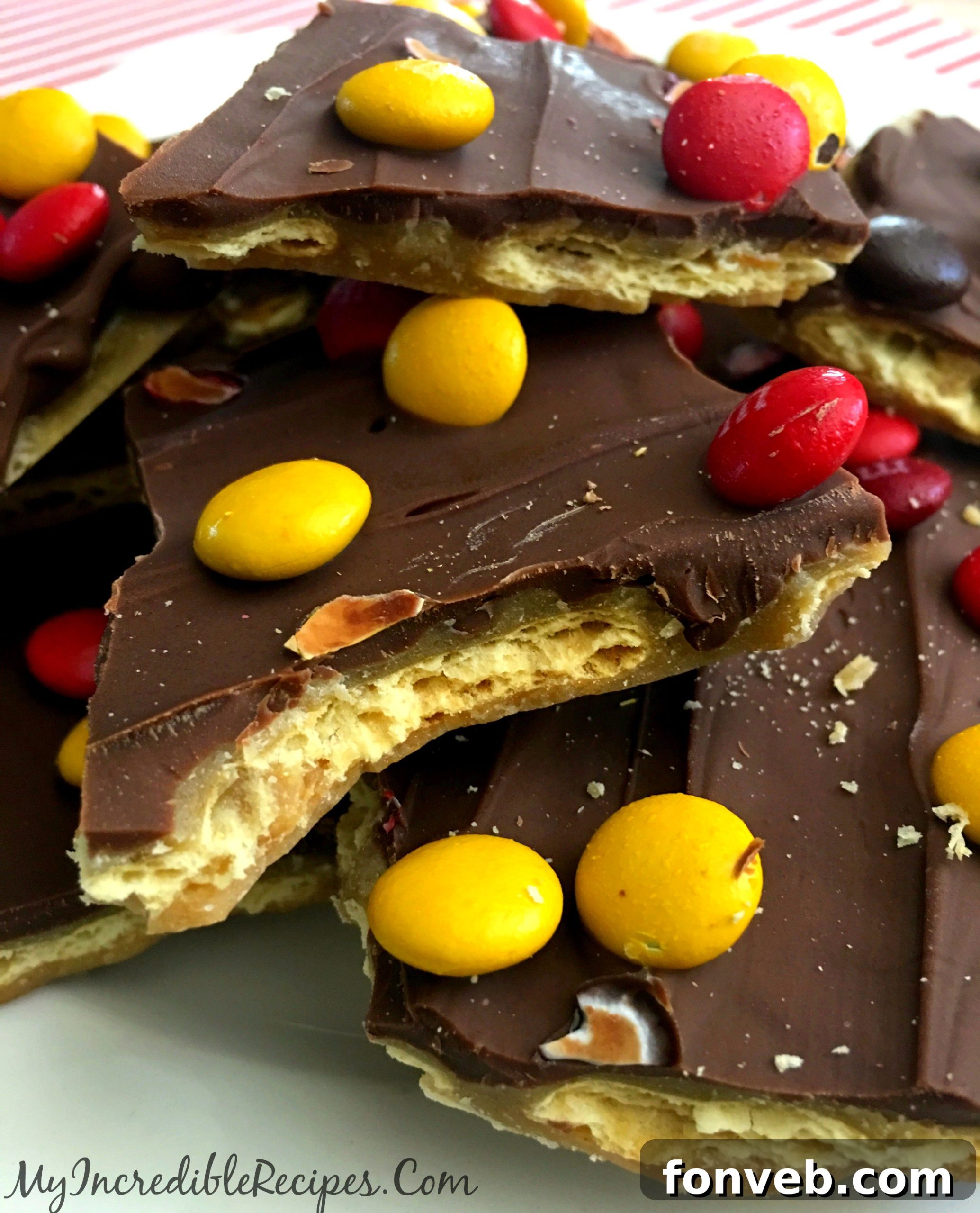 Large, irregular pieces of finished saltine cracker toffee stacked on a white plate