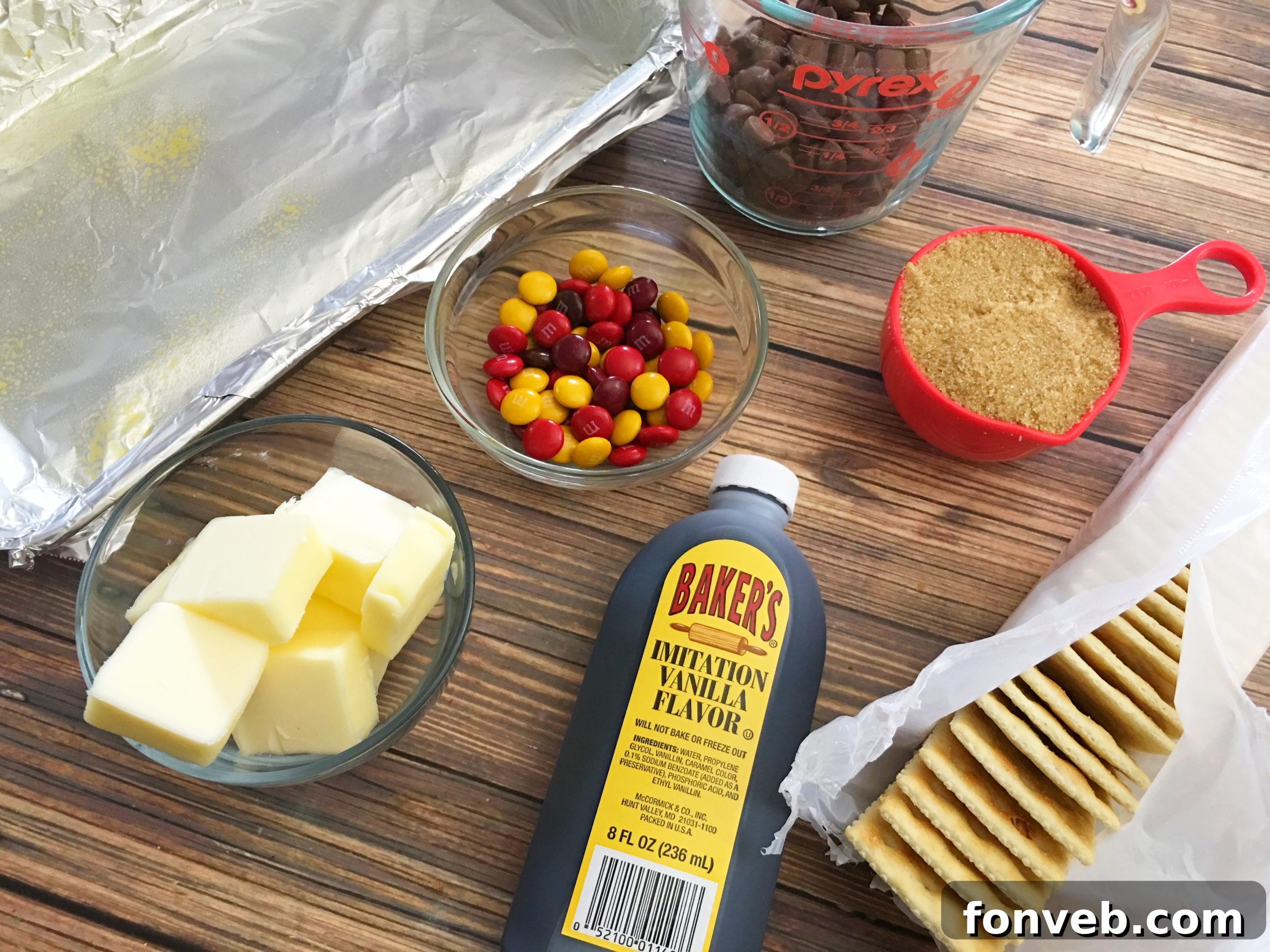 Simple ingredients laid out for making saltine toffee: butter, brown sugar, vanilla, and crackers