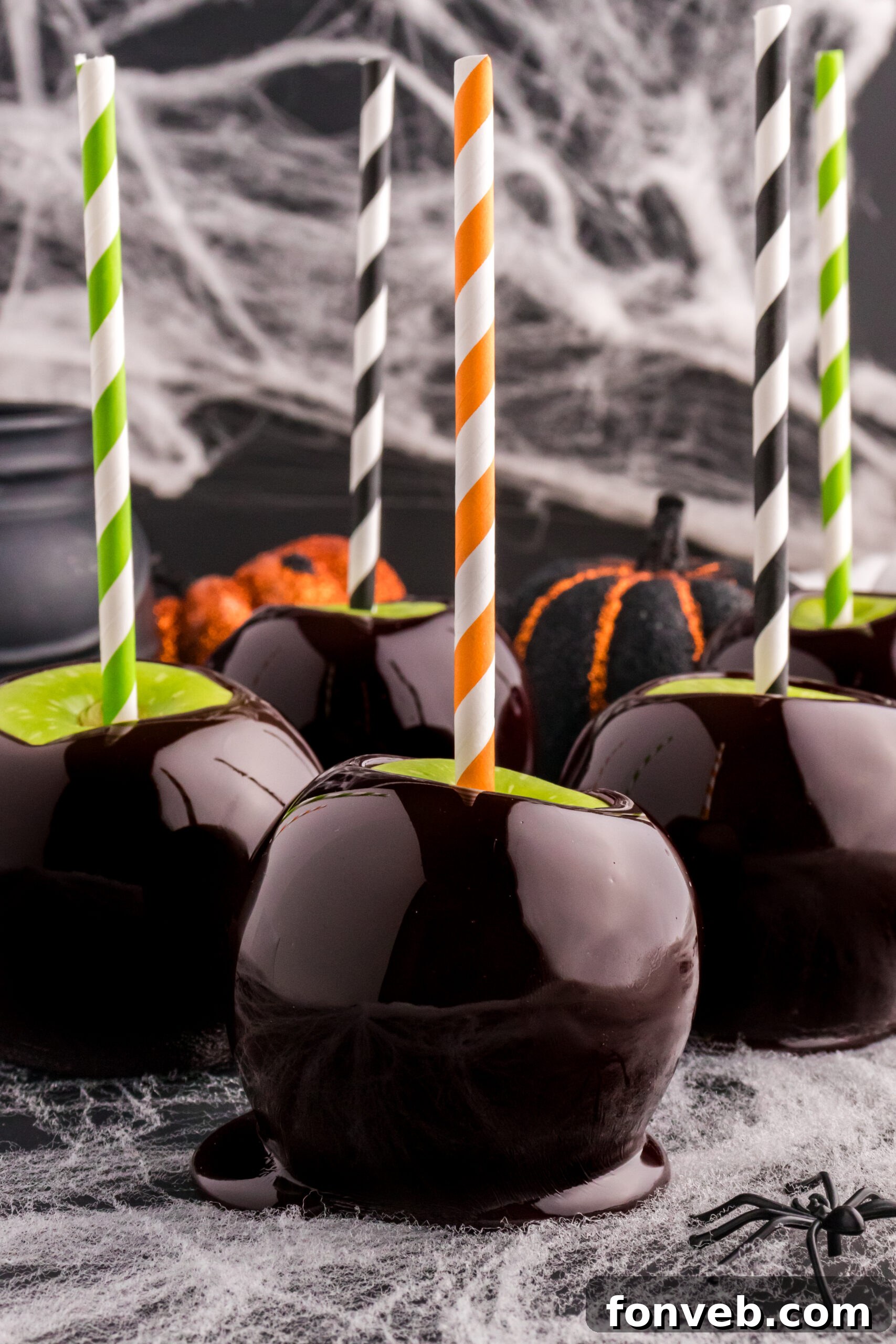 Halloween Candy Apples on a black table with fake cobwebs behind them 
