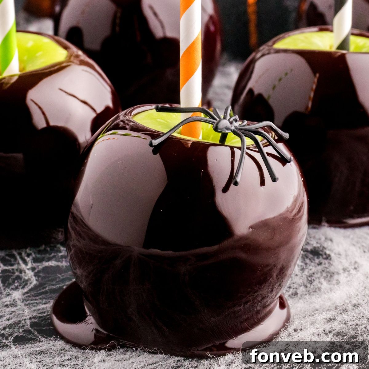 Black Candy Apples on table with fake spider sitting on top of it