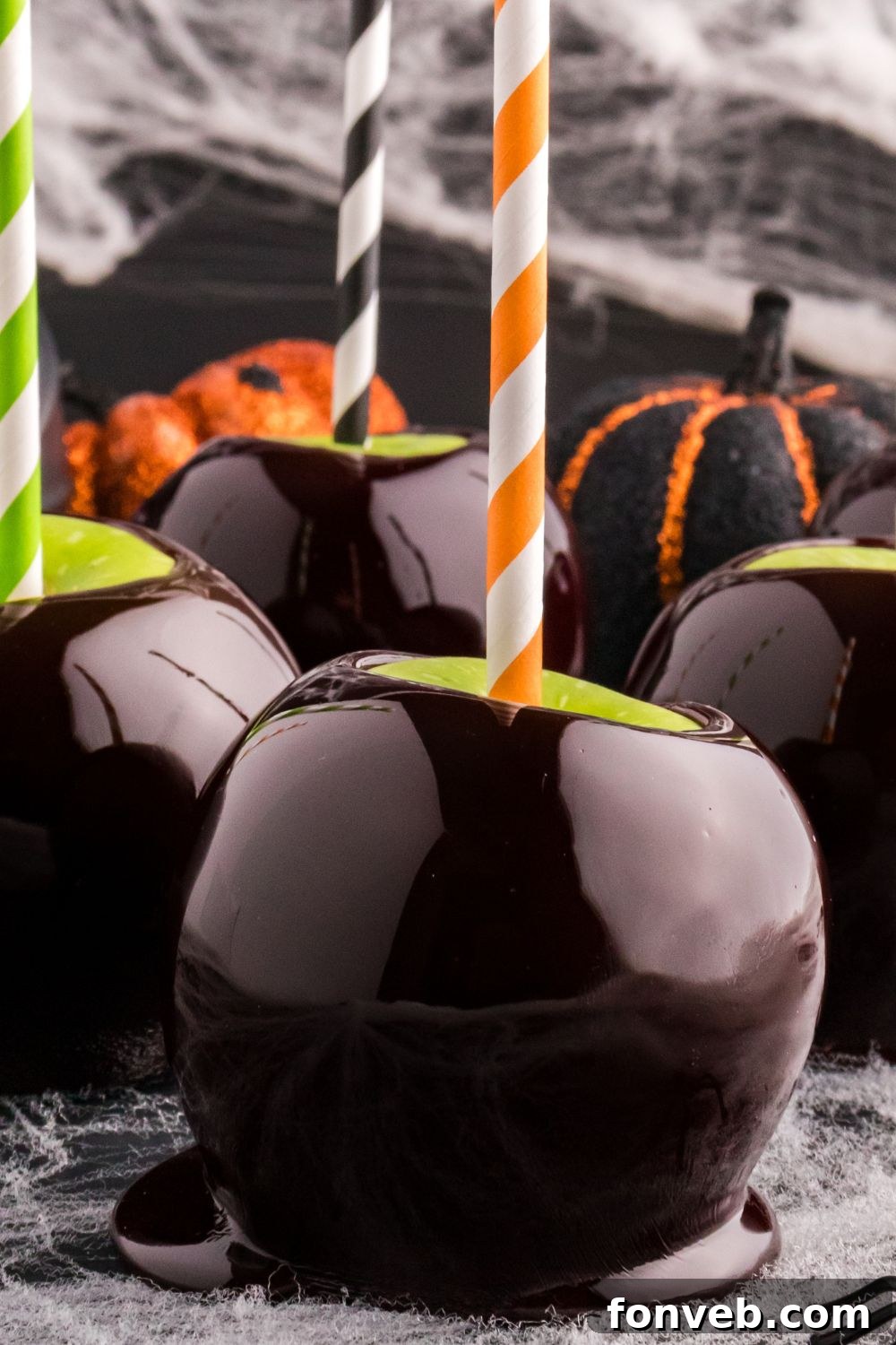 black caramel apples on counter with spider webs around it