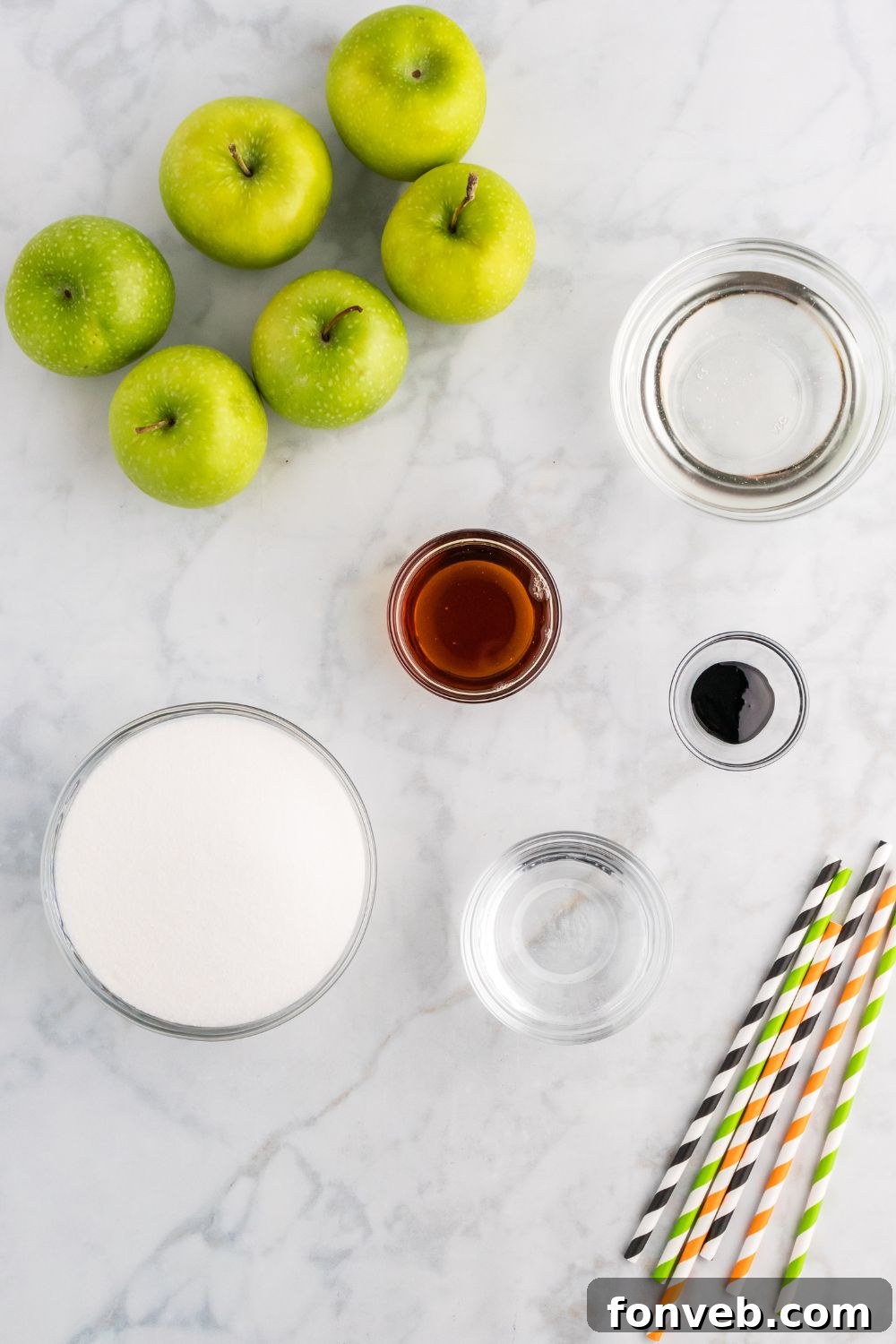 ingredients to make black candy apples sitting on marble counter top