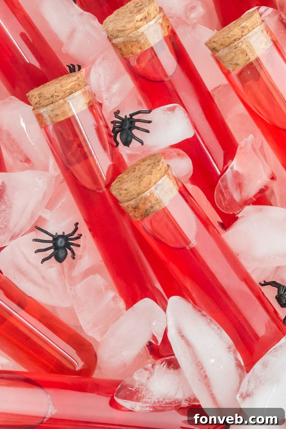close up of red test tubes in container with ice cubes and fake spiders