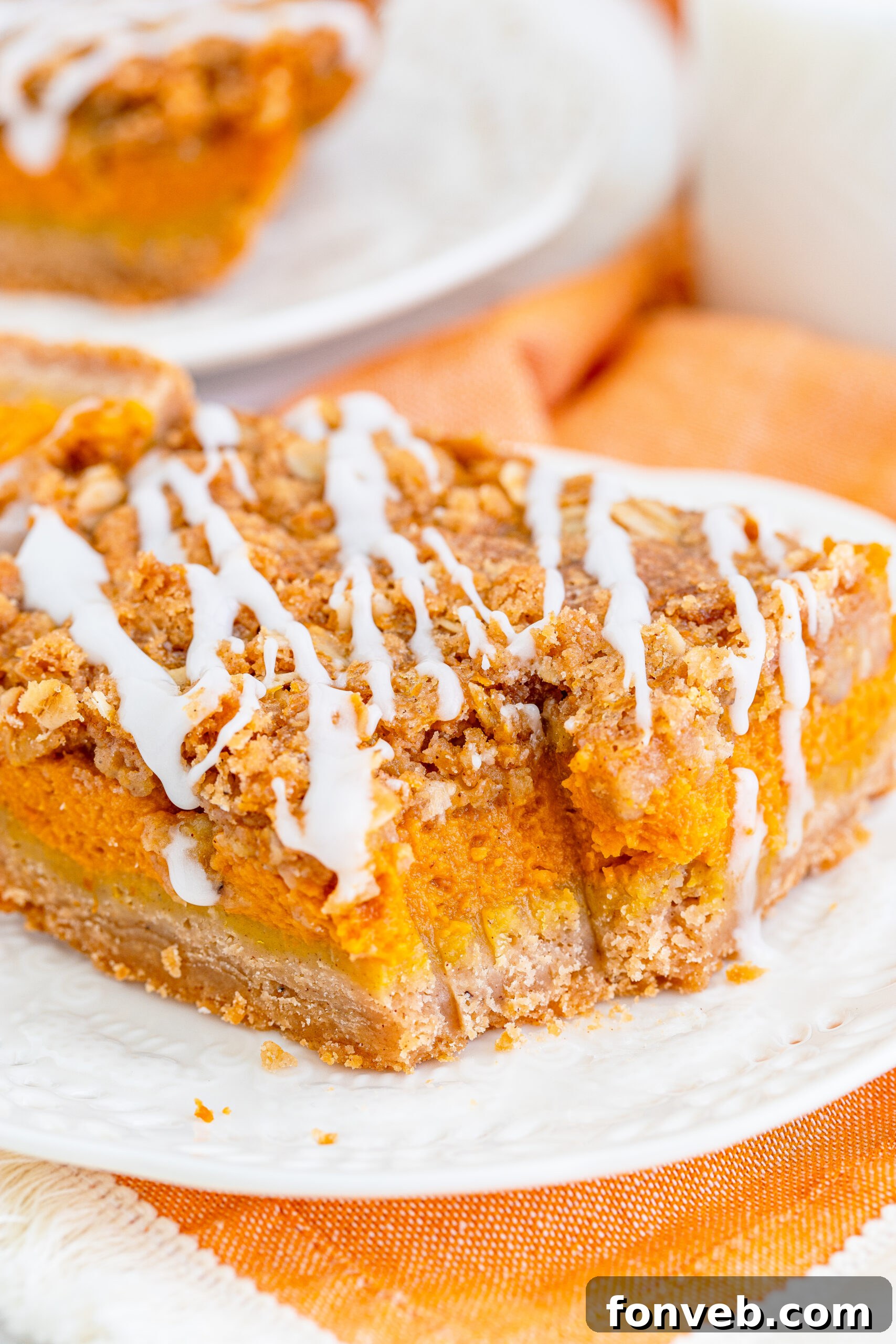 Pumpkin Streusel Bars on a white plate drizzled with glaze