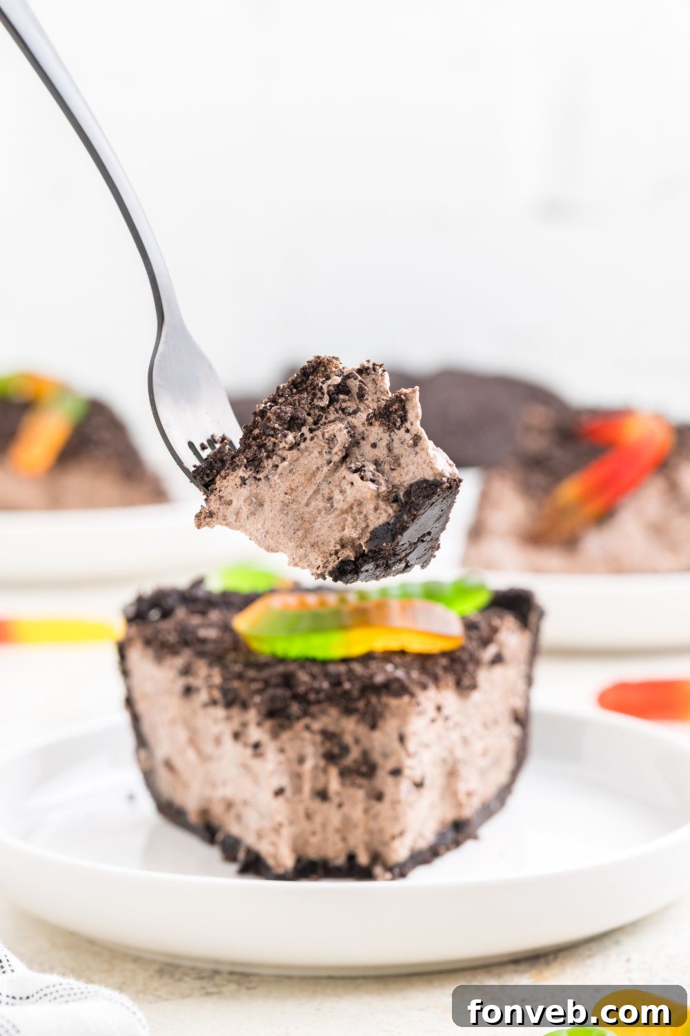 bite taken out of dirt pie on a plate with a slice taken out