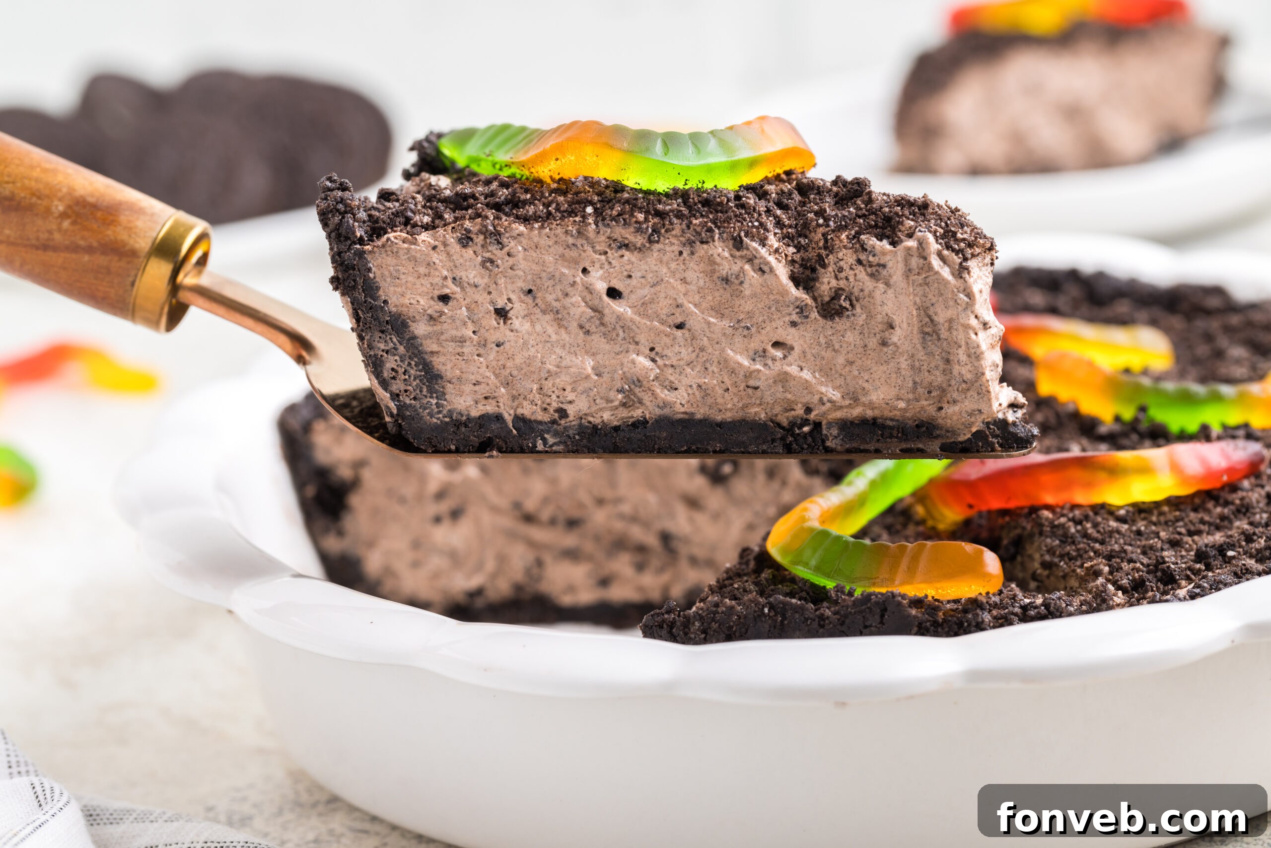 up close shot of oreo dirt pie slice being lifted up by a spatula