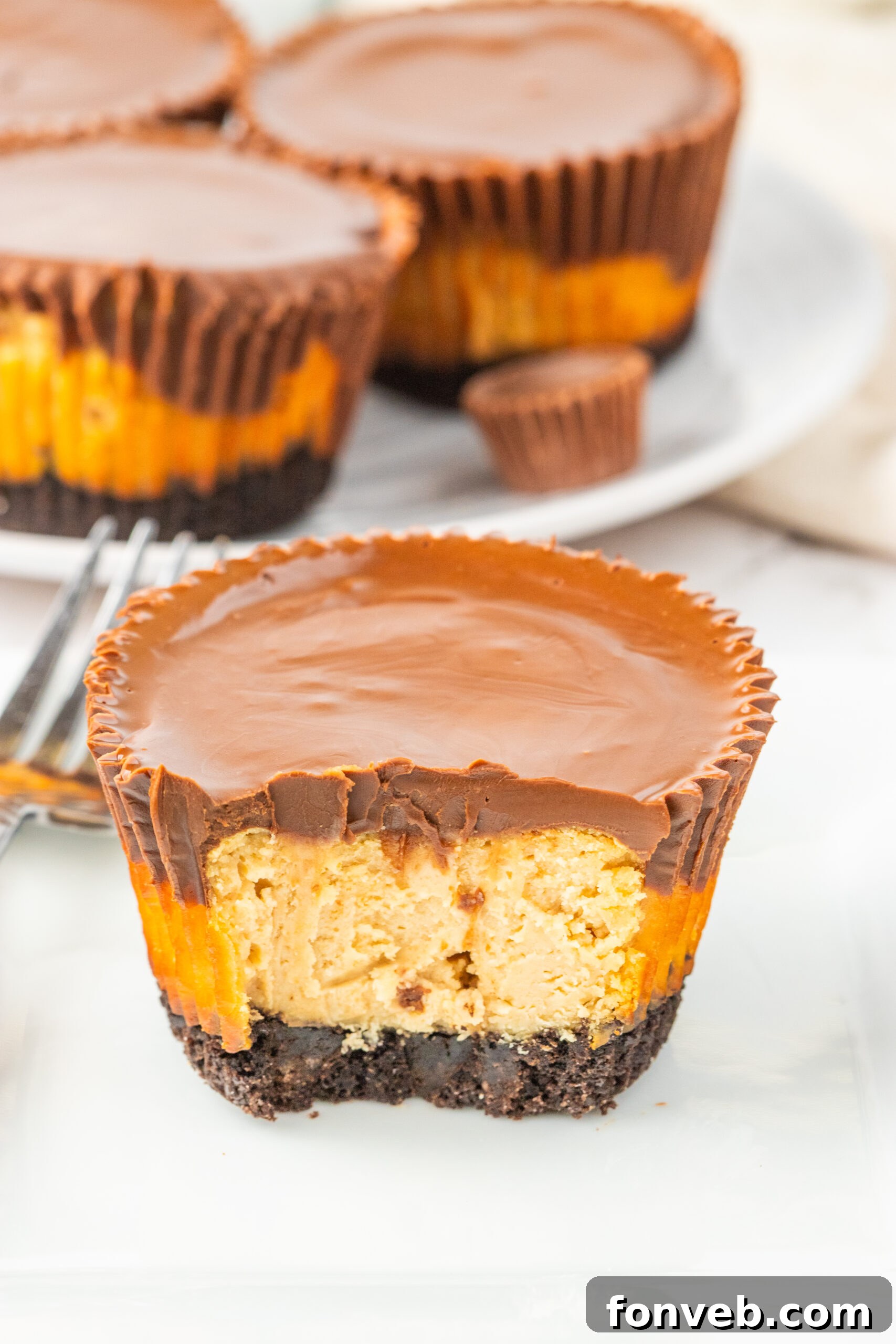 Peanut Butter Cheesecake Bite cut in half and sitting on table, showcasing the layers of crust, filling, and topping.