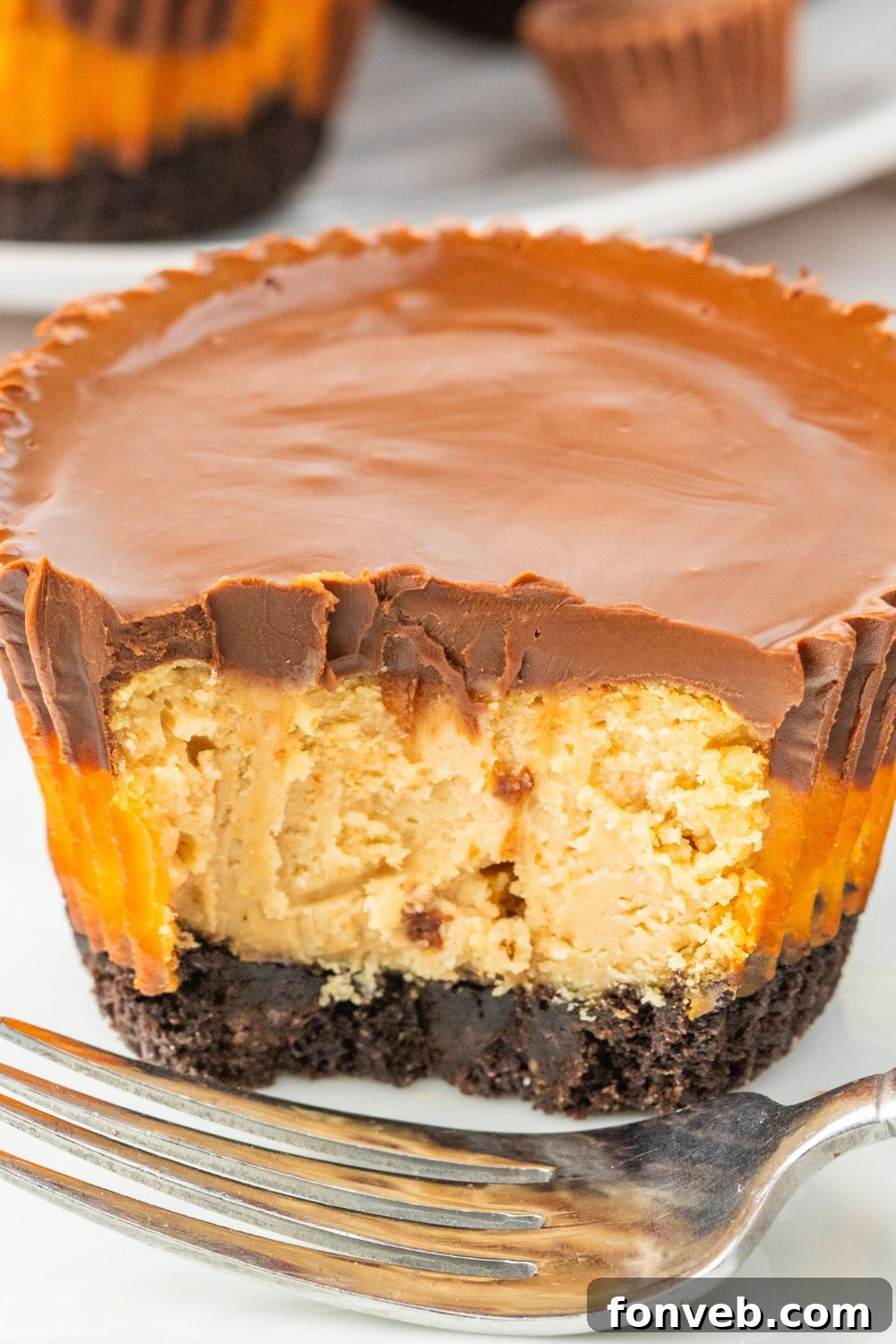 A mini cheesecake with a bite taken out, resting on a small white plate, showing the creamy interior.