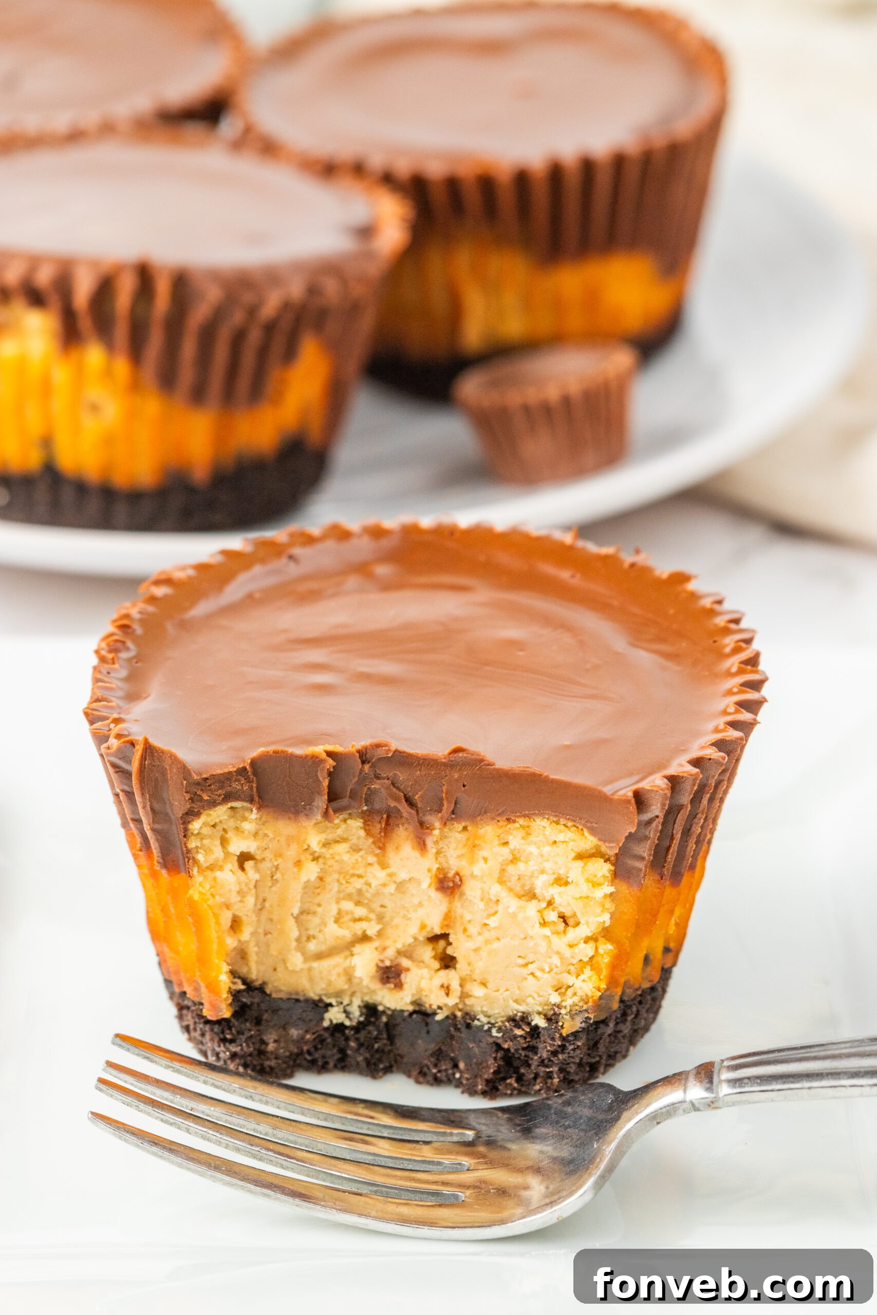 A mini Peanut Butter Cheesecake Bite, cut in half and placed on a table, displaying the thick layers.