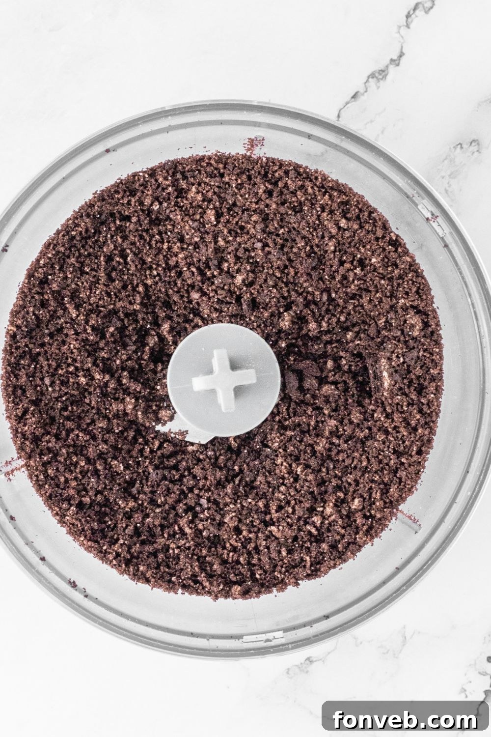 Crushed Oreo cookies in a food processor, ready for the cheesecake crust.