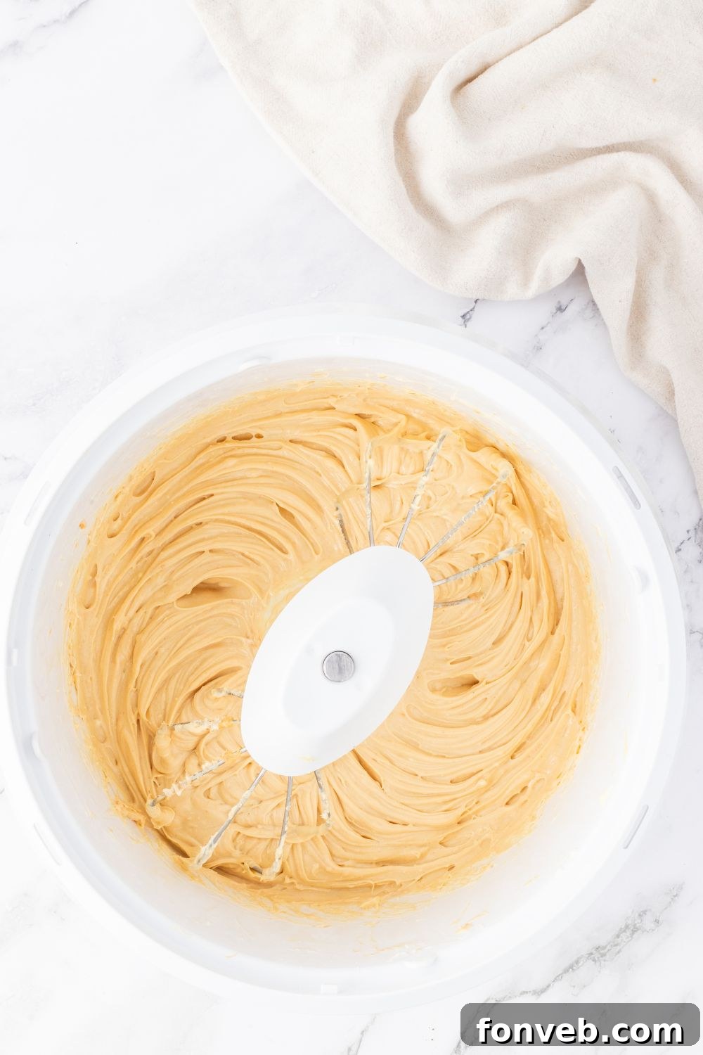 A stand mixer with creamy peanut butter cheesecake filling, ready to be poured.