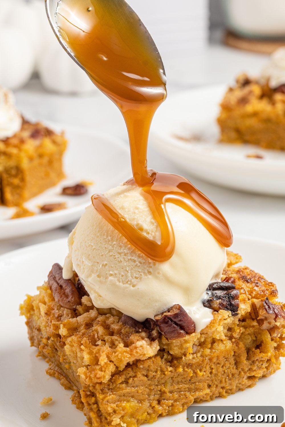 A hand drizzling golden caramel sauce generously over the top of a freshly baked Pumpkin Dump Cake in its pan, enhancing its visual appeal and sweetness.
