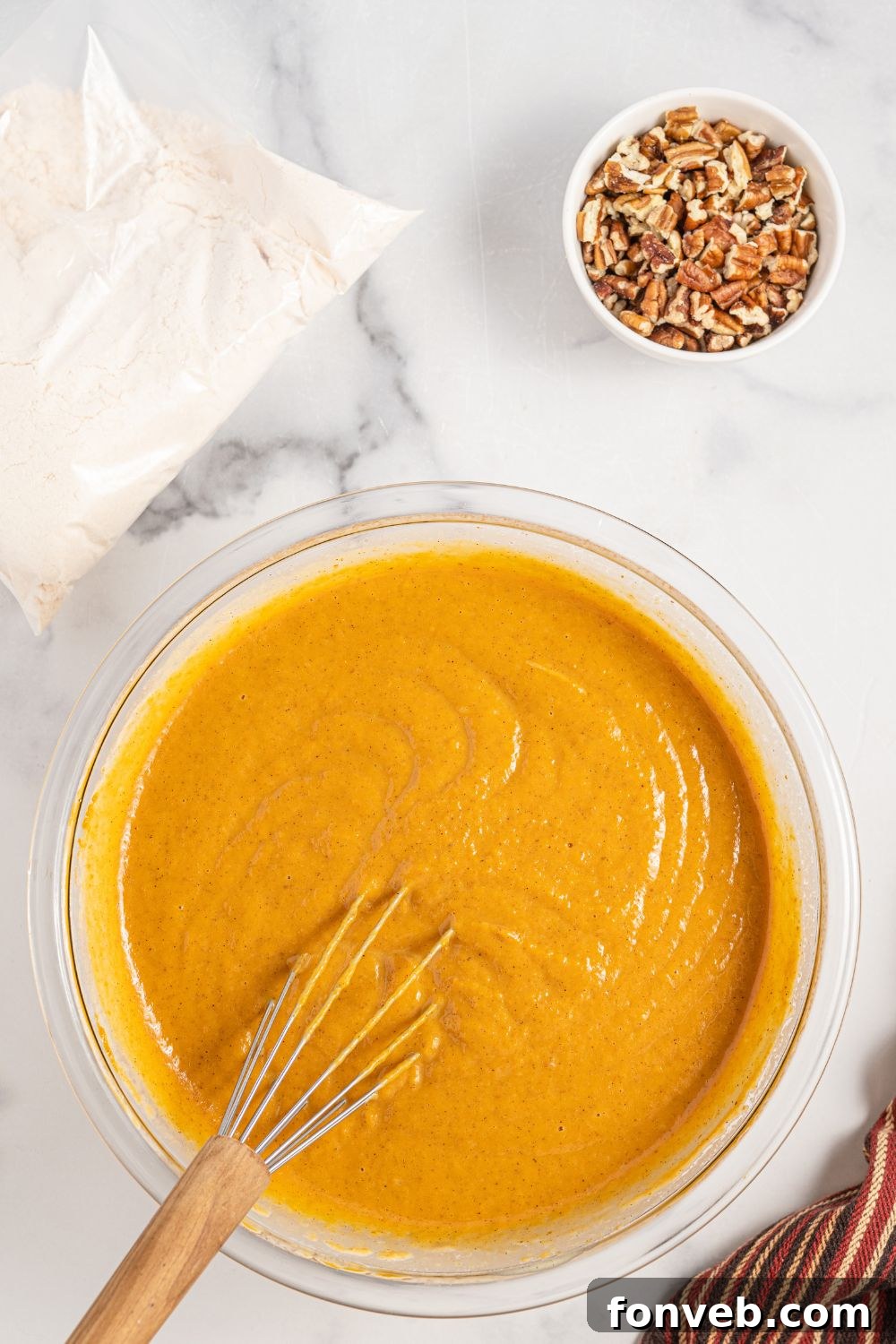 A smooth and vibrant orange pumpkin pie mix, perfectly combined, resting in a glass bowl, ready to be poured into the baking dish.