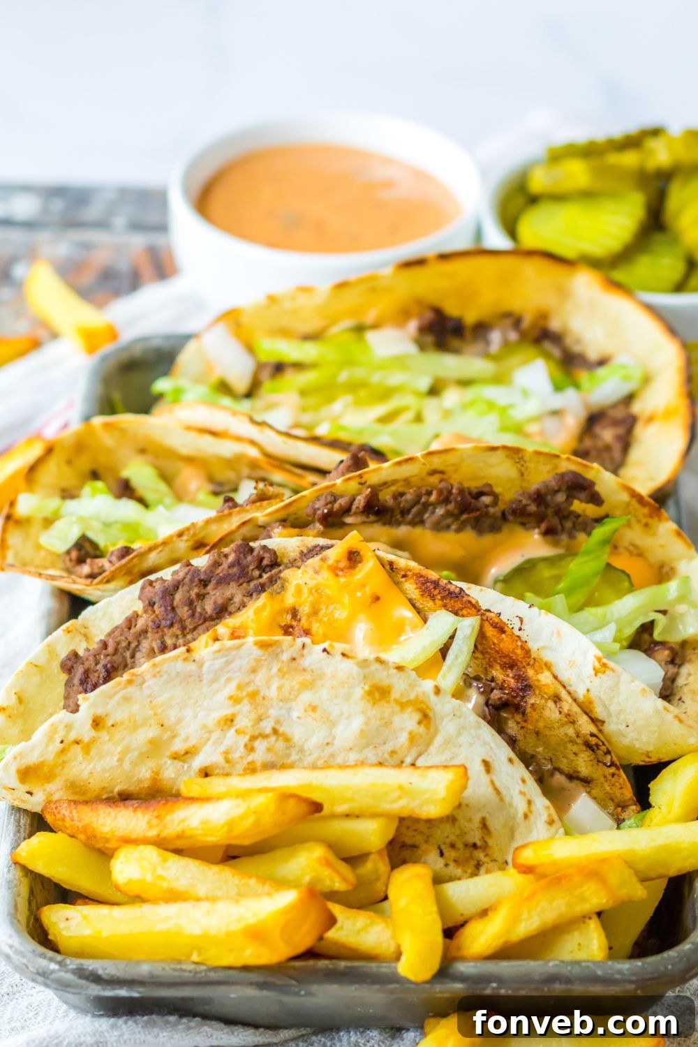 Smashed Big Mac Tacos 15 Big Mac smash tacos and french fries on a table with condiments in small containers