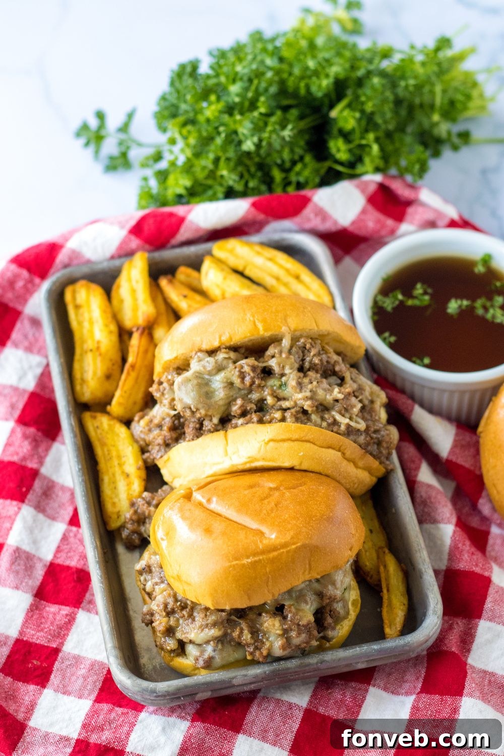 beef au jus sandwiches on a tray with red plaid napkin under it