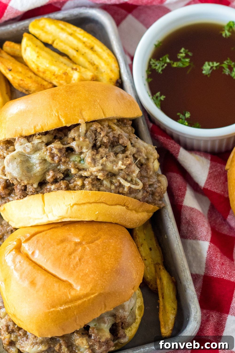 french dip sauce in bowl and sandwiches on side