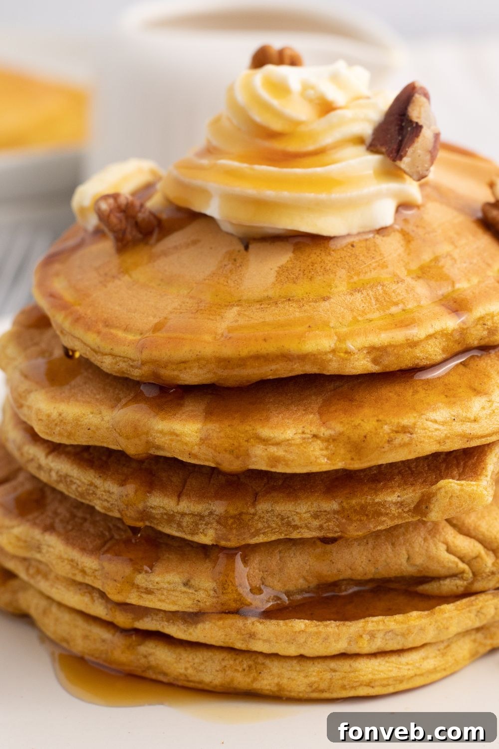 stack of pancakes on plate with whipped cream and nuts on top