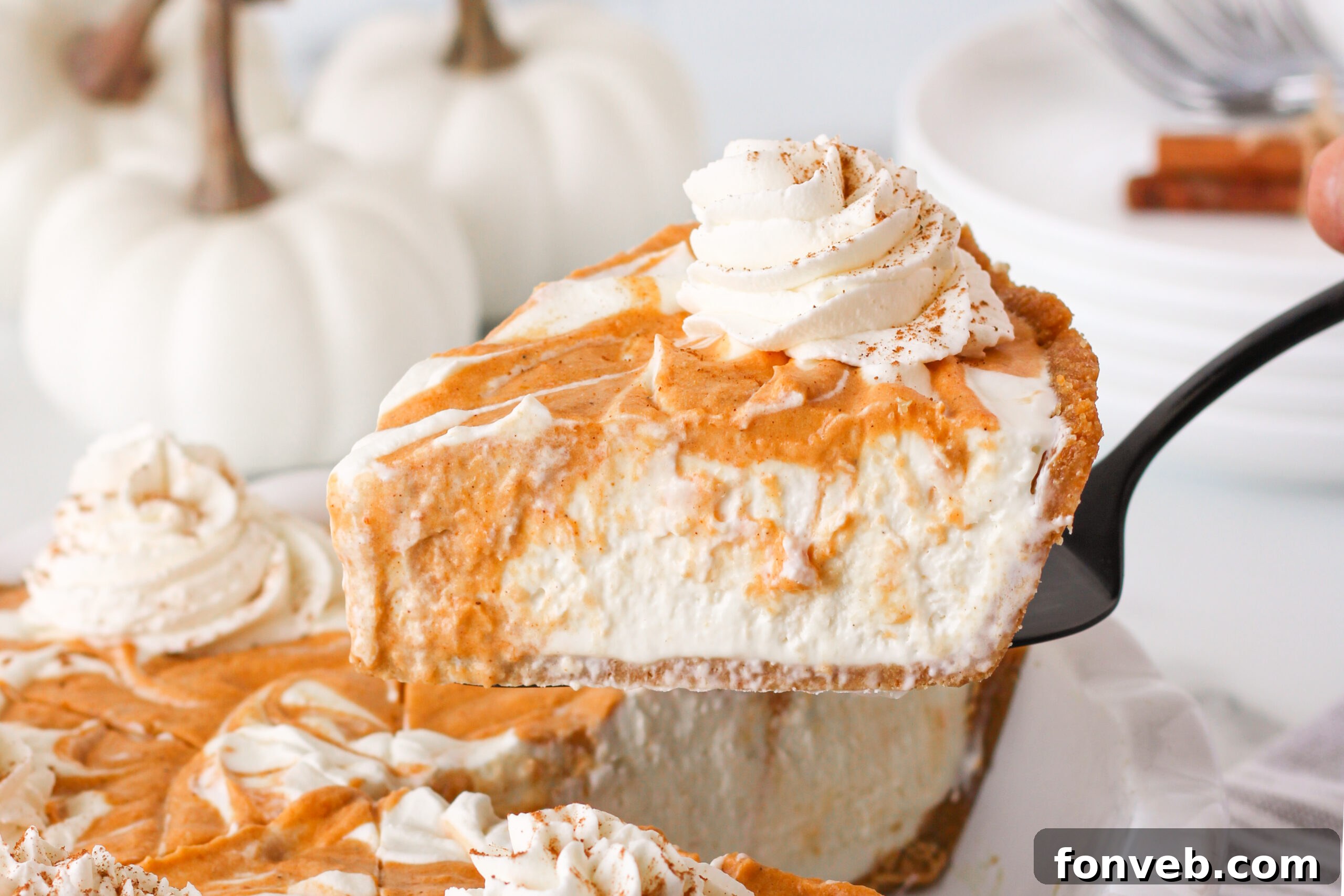 Spiced Pumpkin Ice Cream Pie 15 Pumpkin Ice Cream Pie in a white baking dish with a slice being lifted up on a serving spoon