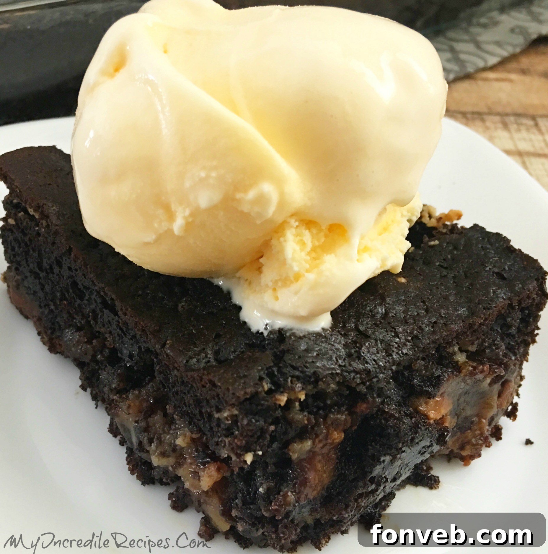 A slice of warm Peanut Butter Earthquake Cake topped with a scoop of melting vanilla ice cream