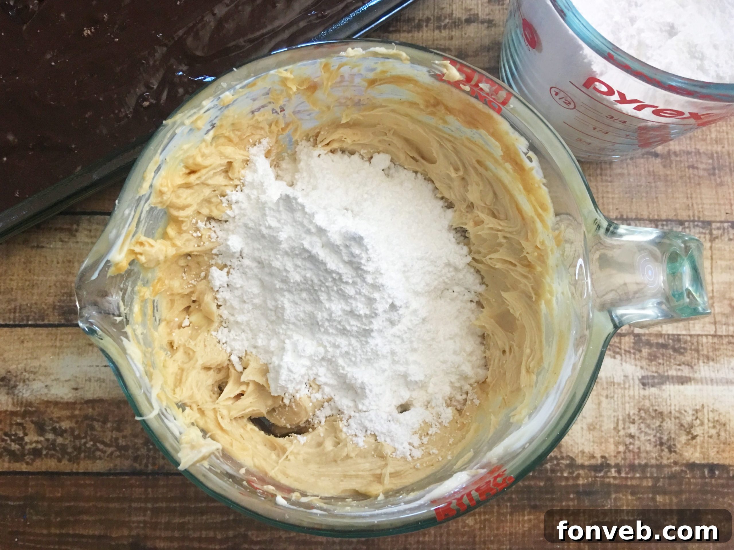 Bowl of chocolate cake batter being mixed, with a hand holding a spatula, ready to be poured