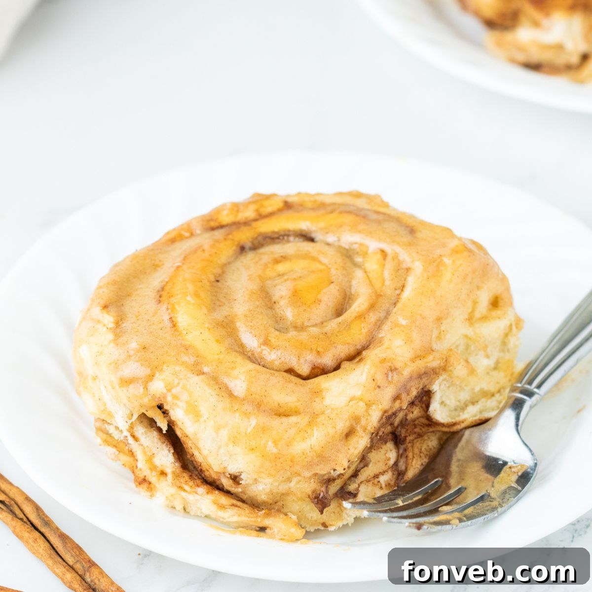 Pumpkin Cinnamon Roll on plate with a fork on the side