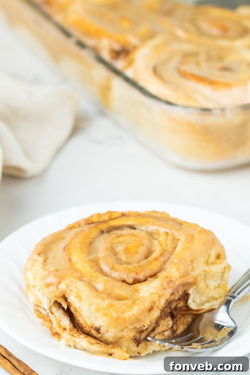 cinnamon roll on plate with casserole with more rolls