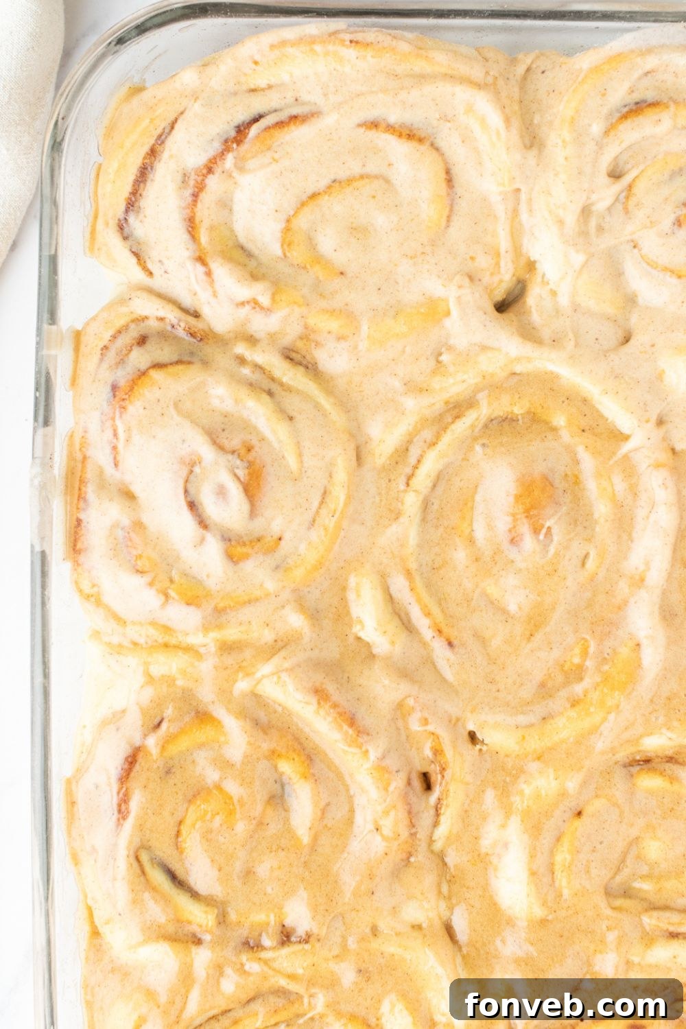 overhead shot of pumpkin cinnamon rolls in a glass pan on table