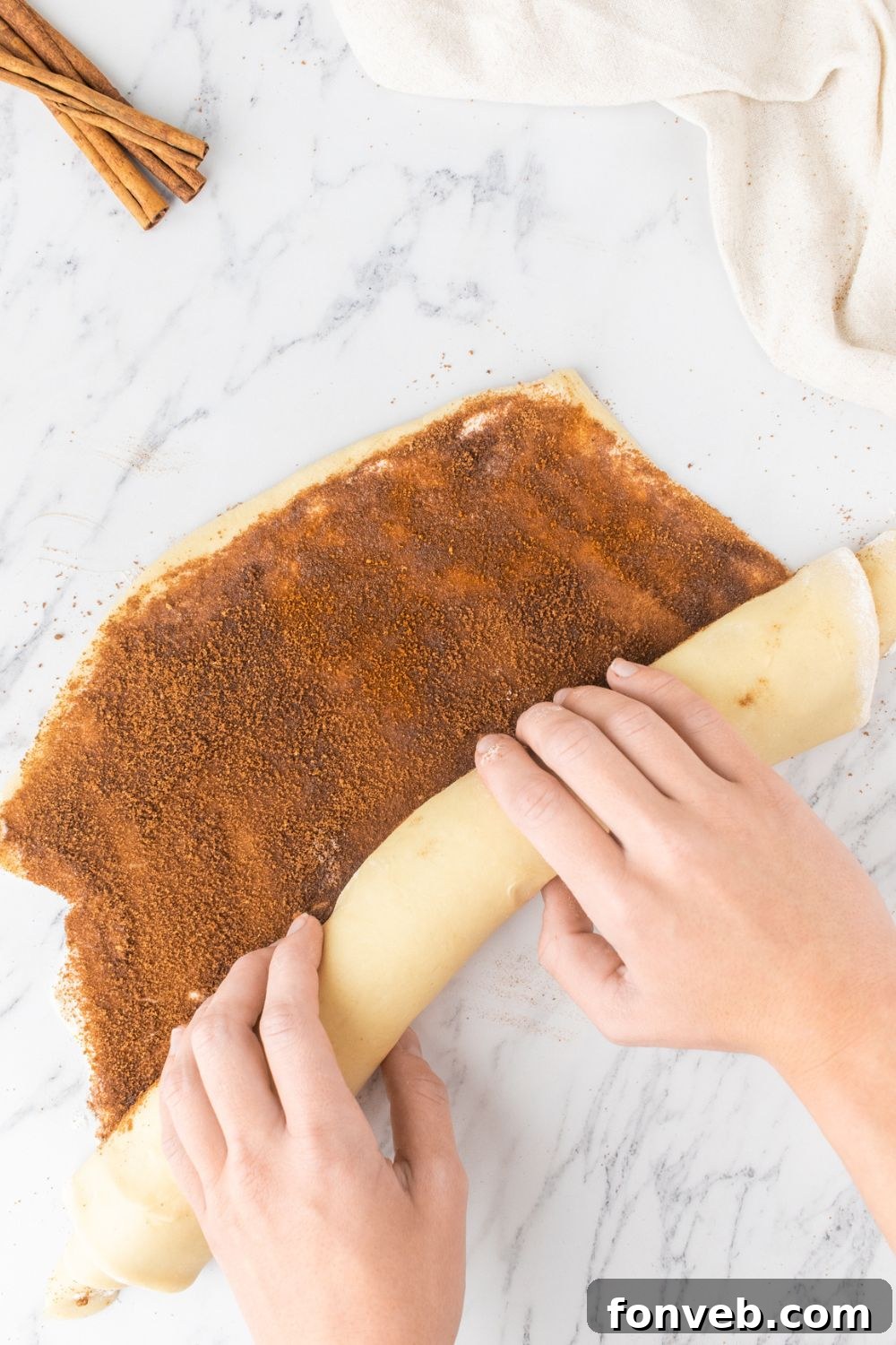 rolling cinnamon roll dough into a rolled tube 