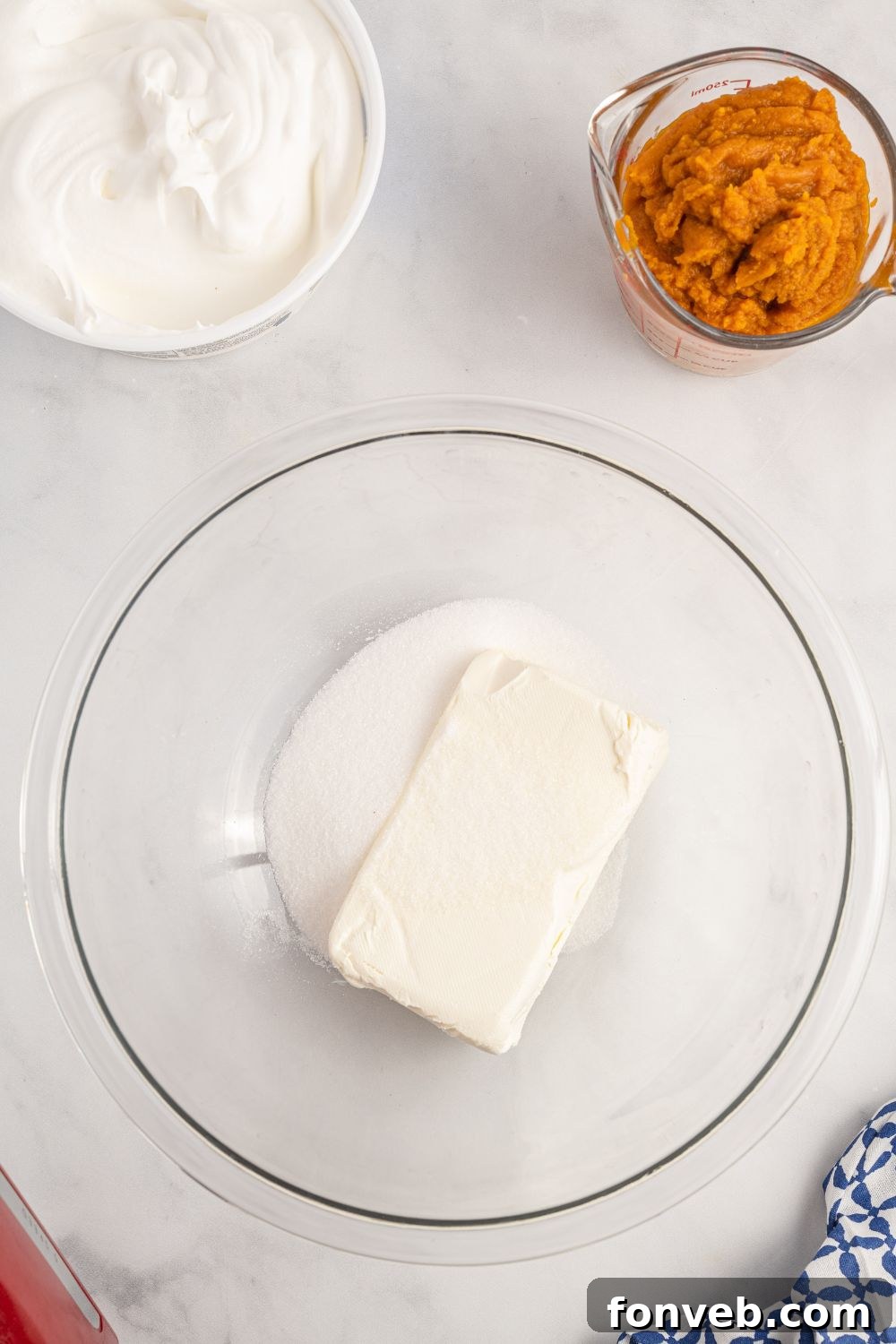 Softened cream cheese in a glass mixing bowl, ready for the cream cheese layer.