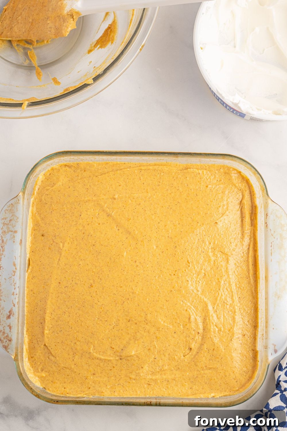 The pumpkin pudding layer spread evenly over the cream cheese layer in an 8x8 baking pan, showing distinct layers.