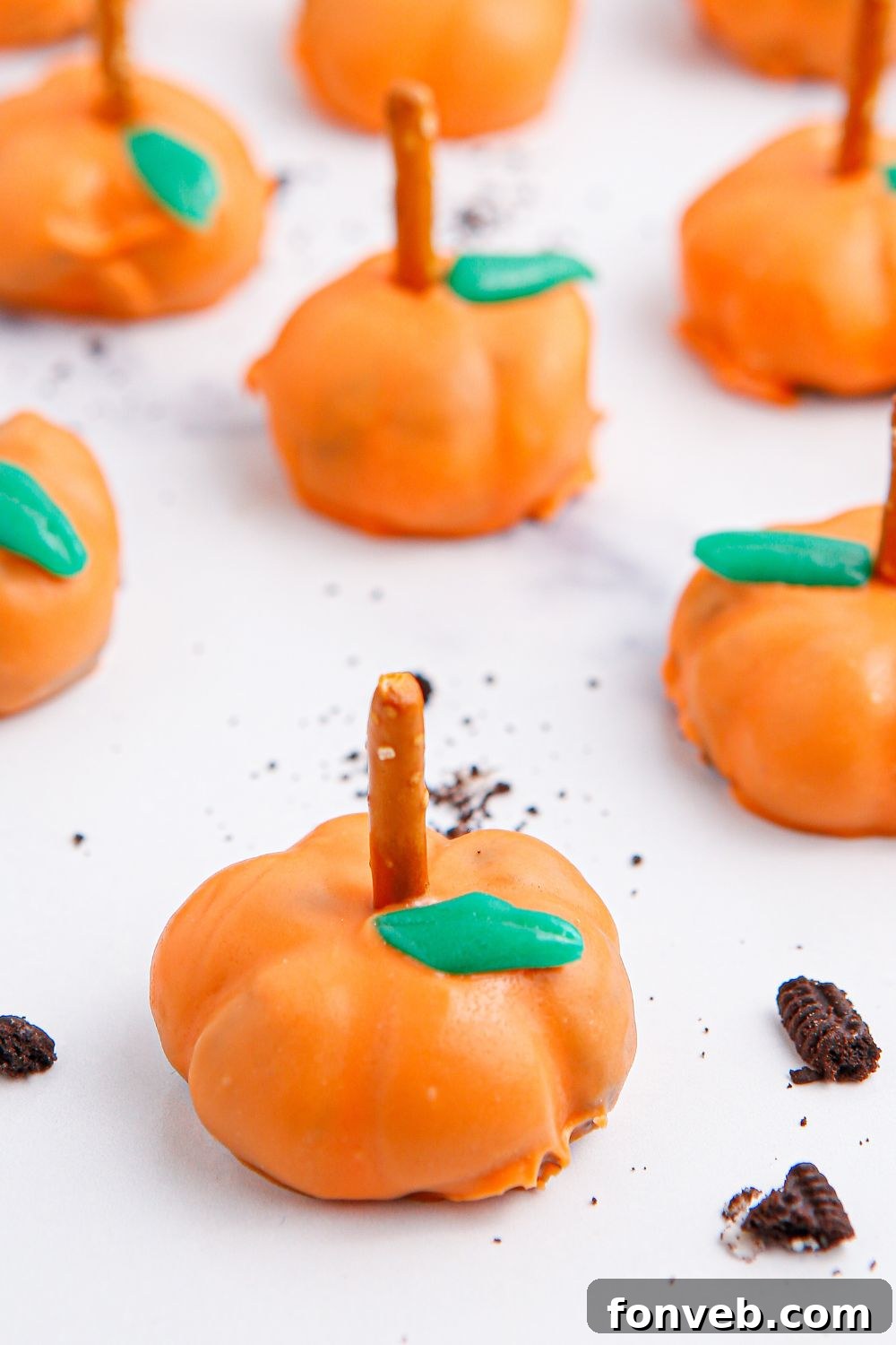 Pumpkin Spiced Oreo Truffles 14 pumpkin oreo cheesecake bites on white table with cookie crumbles around it