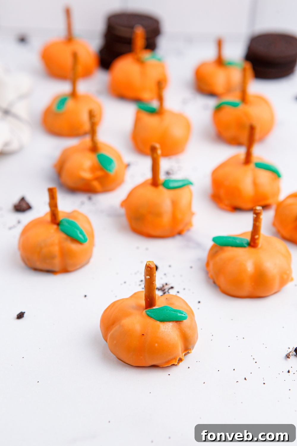 Pumpkin Spiced Oreo Truffles 16 Oreo truffles sitting on table with cookies stacked up behind it
