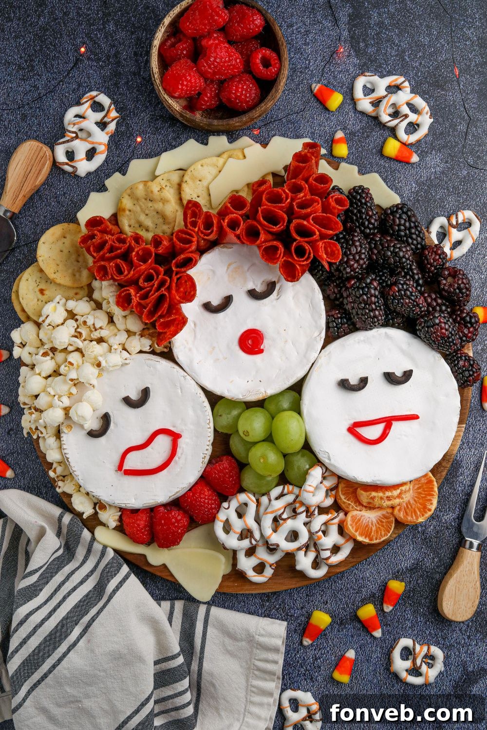 An inviting overhead shot of the completed Hocus Pocus Charcuterie Board, clearly displaying the Sanderson Sisters made from Brie and the rich variety of snacks surrounding them.