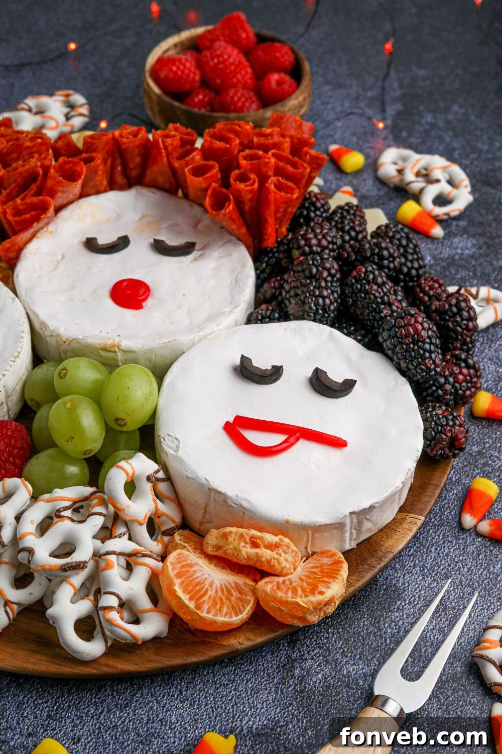 Three Brie cheese wheels artfully decorated as the Sanderson Sisters from Hocus Pocus, forming the central display of a Halloween charcuterie board.