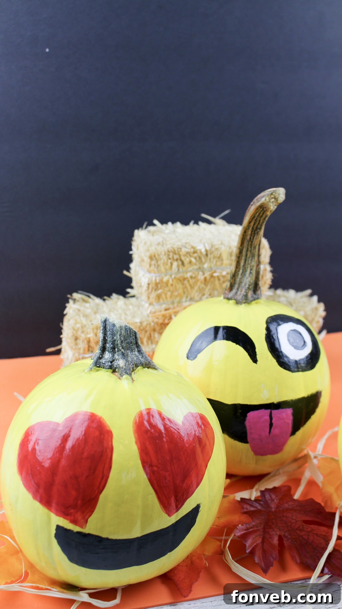 Pumpkins with Personality 15 A charming vignette of DIY emoji pumpkins alongside other autumnal decor like mini hay bales and flowers, creating a festive display.