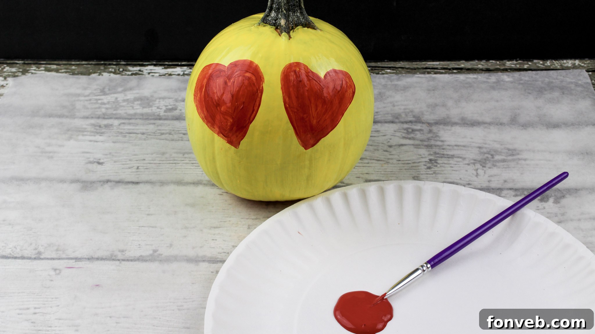Pumpkins with Personality 6 A child's hands carefully painting one of the yellow pumpkins, showcasing the hands-on and family-friendly nature of the craft.