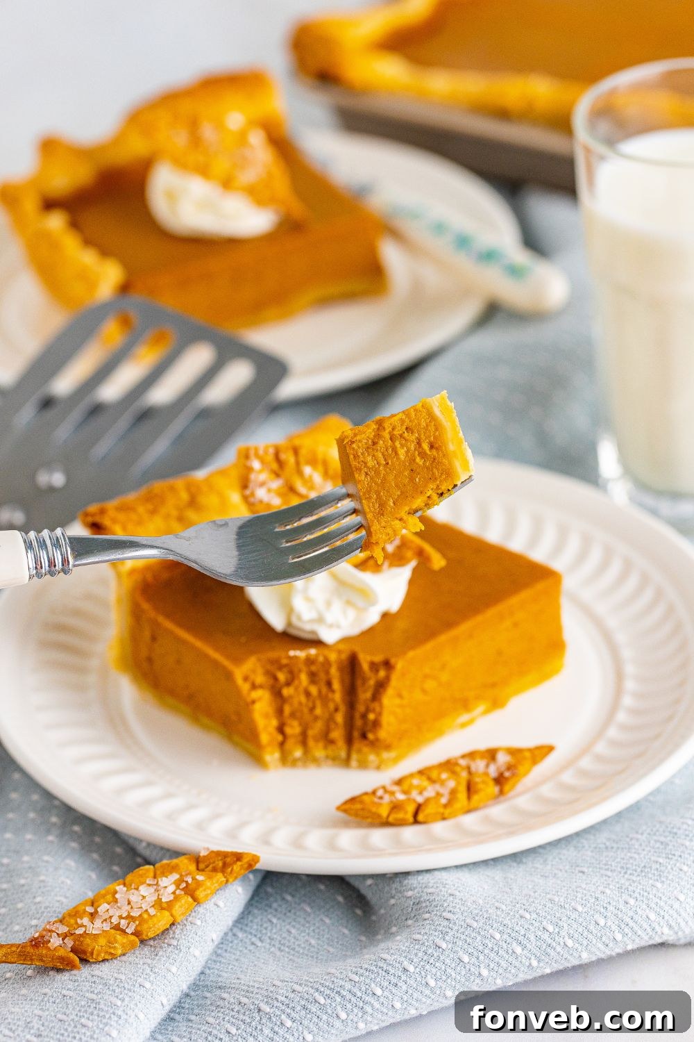 slice of pumpkin pie on plate with bite on a fork