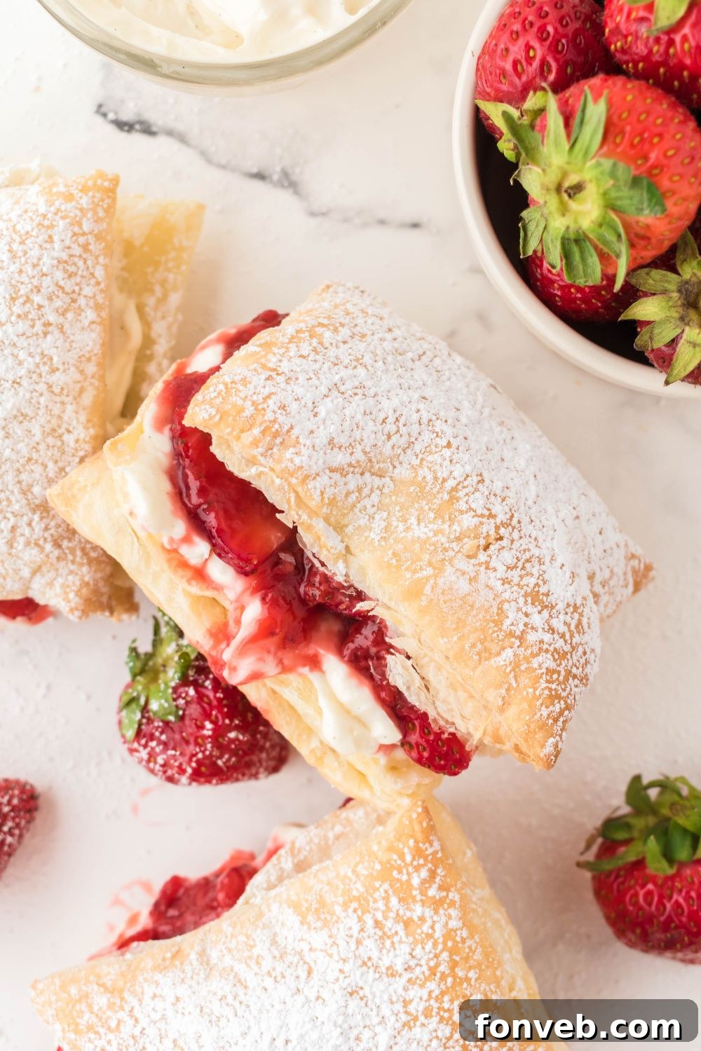 strawberry puffs on plate with a bowl of strawberries on the side on a marble counter