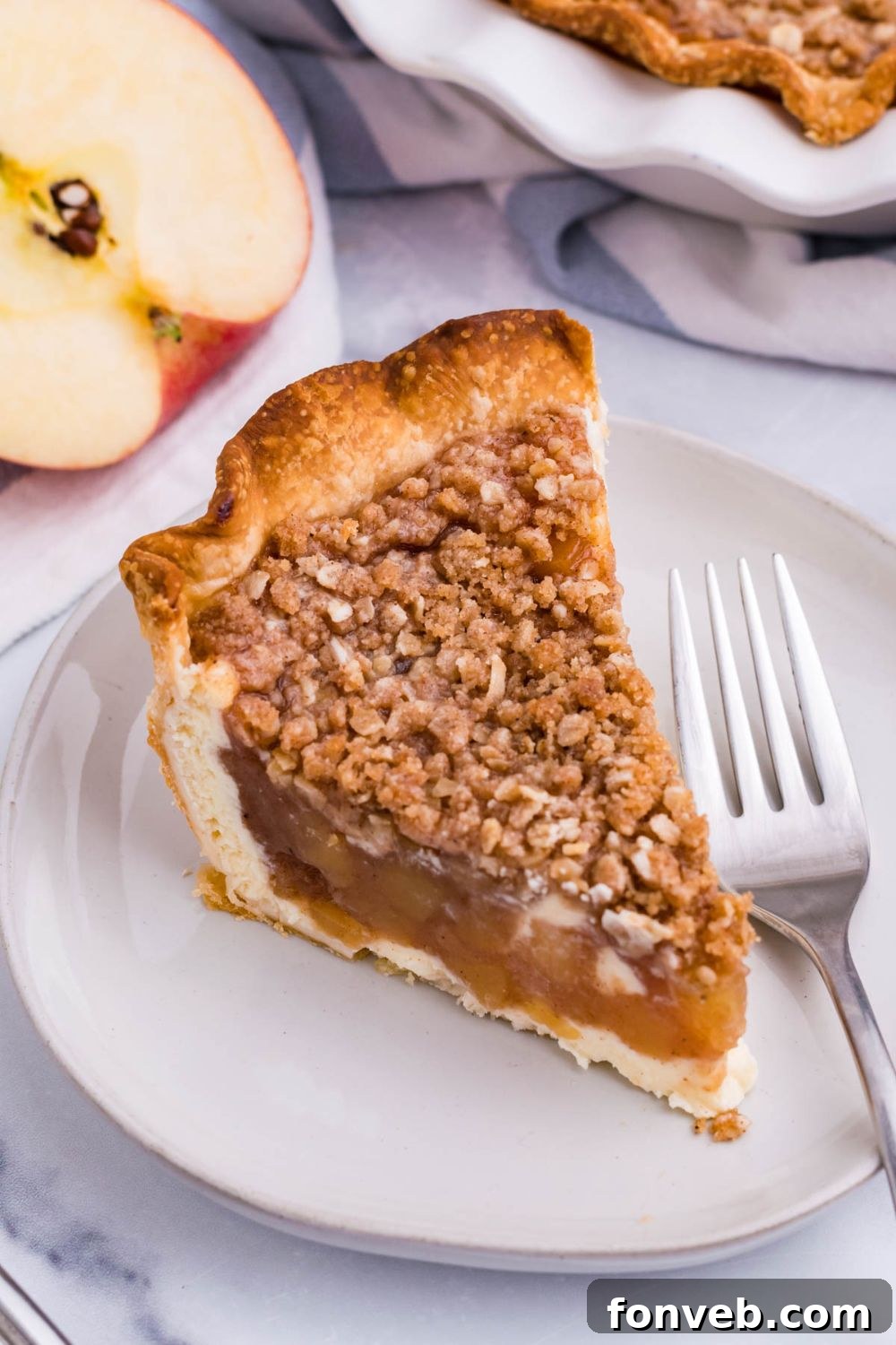 Spiced Apple Crumble Cheesecake Pie 11 apple crumble cheesecake slice on plate with fork and apple on the side
