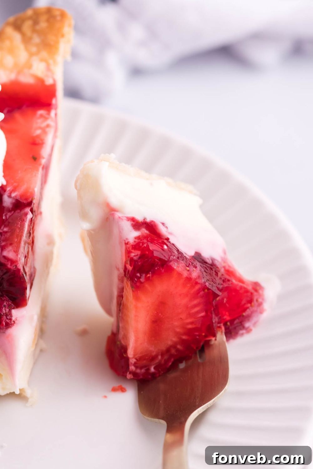 A close-up of a fork full of Strawberry Cream Cheese Pie, showing a perfect bite with all the layers, ready to be enjoyed.
