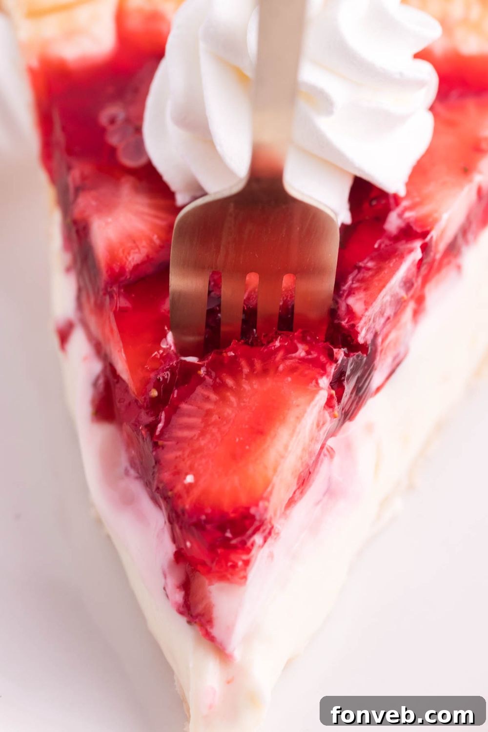 A fork gently piercing into a slice of Strawberry Cream Cheese Pie, illustrating the soft texture of the filling and fruit.