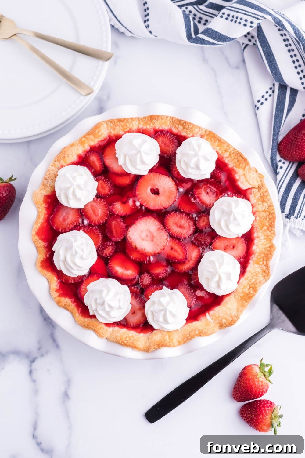 An overhead shot of a Strawberry Cream Cheese Pie on a white plate, showcasing the neatly arranged strawberry slices and the glossy jello setting over the creamy white filling.