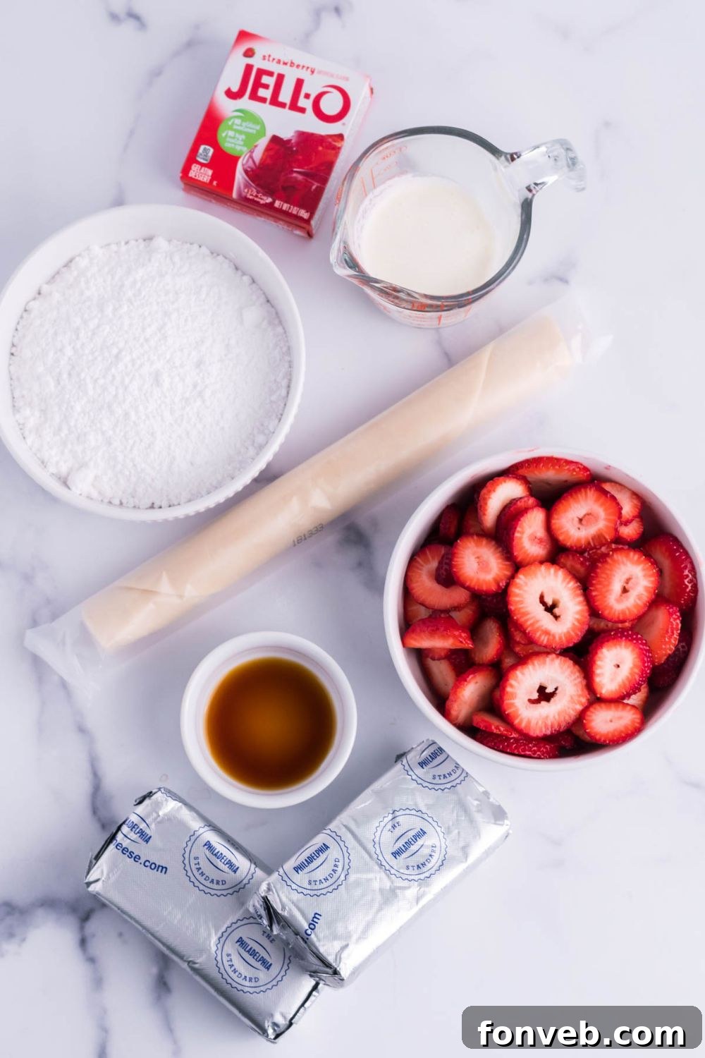 Various ingredients for a cream cheese and strawberry pie laid out neatly on a light marble kitchen counter, including fresh strawberries, cream cheese blocks, powdered sugar, and a pie crust.