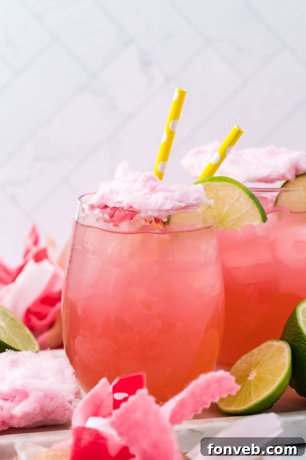 drink with cotton candy on top on table with limes around it