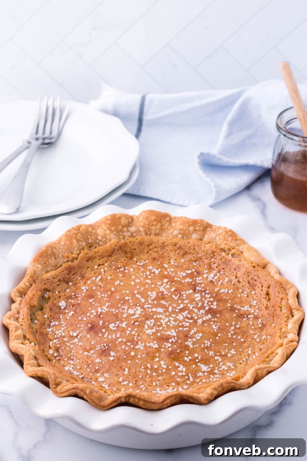 Golden Sweetheart 15 A golden honey pie nestled in a pie pan on a rustic table, surrounded by clean white plates and forks, ready for serving.